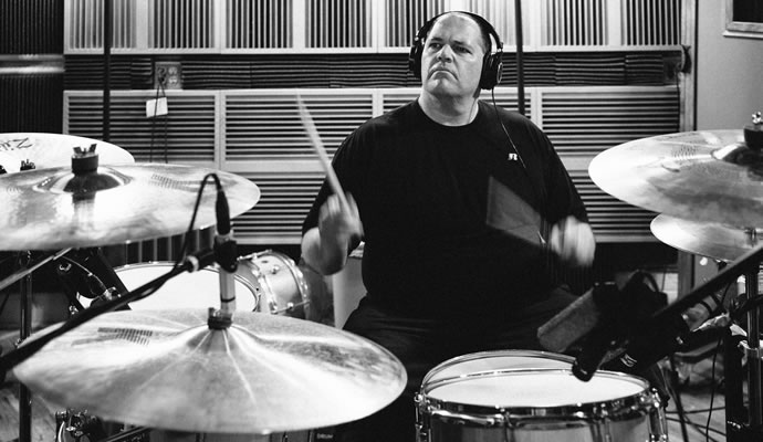 Fotografía blanco y negro de Bill Stevenson tocando batería en estudio